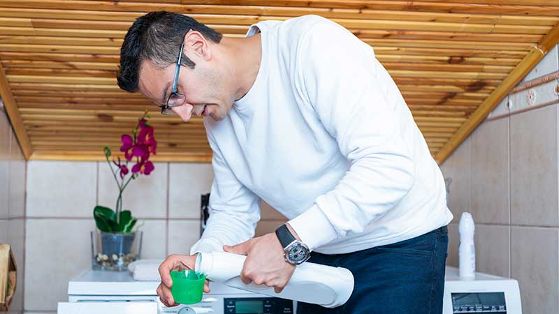 Homem a colocar detergente na tampa doseadora